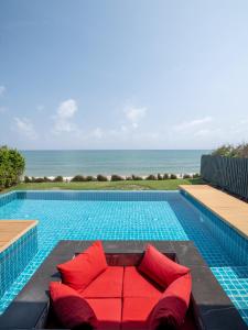 een zwembad met een rode bank naast de oceaan bij Sunshine Paradise Resort in Ban Krut