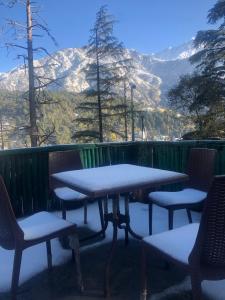 a table and chairs on a deck with snow covered mountains at Rana's House, Mcleodganj in McLeod Ganj
