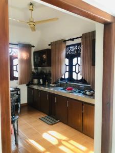 una cocina con armarios de madera y ventanas en una habitación en Akesha's House, en Weligama
