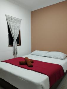 a bed with a red blanket and a window at Lawer Guesthouse (Pulau Langkawi) in Pantai Cenang