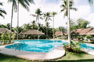 - une piscine dans un complexe avec des palmiers dans l'établissement Commander Suites de Bohol, à Panglao