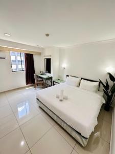 a white bedroom with a large bed and a desk at Swing & Pillows - Corona Inn Bukit Bintang in Kuala Lumpur
