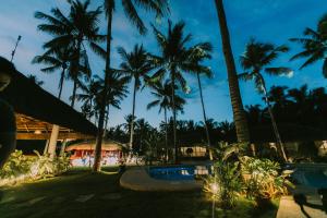 a view of a resort with palm trees at night at Commander Suites de Bohol in Panglao Island