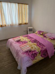 a bedroom with a bed with a pink and yellow blanket at La Mezcla Perfecta Hostal in Managua