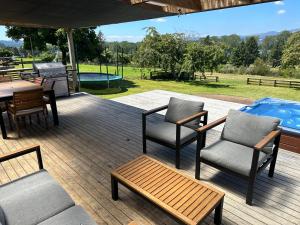 um pátio com cadeiras, uma mesa e comodidades para churrascos em Lake Holiday Home - Spa & Views em Mangakino