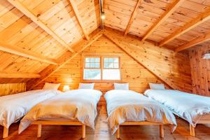three beds in a room with a wooden ceiling at 森のや in Shimo-sagano