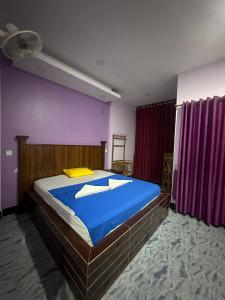 een slaapkamer met een bed met blauwe lakens en paarse muren bij The Vibe Guesthouse in Kampot