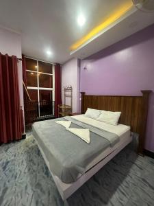 een slaapkamer met een groot bed met een paarse muur bij The Vibe Guesthouse in Kampot