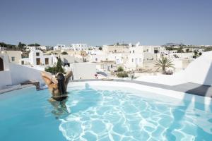 a man in a swimming pool with a view of buildings at Simantiri Private Villa in Megalochori