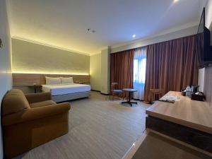 Habitación de hotel con cama y sofá en Grand Verona Samarinda, en Samarinda
