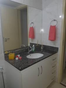 eine Badezimmertheke mit einem Waschbecken und einem Spiegel in der Unterkunft Apartamento in Rio de Janeiro