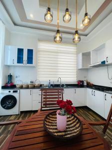 a kitchen with white cabinets and a table with red flowers at ORANGE LIMITED TANZANIA in Dar es Salaam