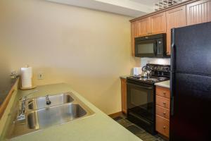 a kitchen with a sink and a black refrigerator at 2203 - One Bedroom Den Standard Eagle Springs East condo in Solitude