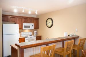 eine Küche mit einem weißen Kühlschrank und einer Uhr an der Wand in der Unterkunft 3313 - One Bedroom Den Standard Powderhorn Lodge condo in Solitude
