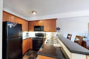 a kitchen with a black refrigerator and wooden cabinets at 2307- Two Bedroom Den Deluxe Eagle Springs East Hotel Room in Solitude