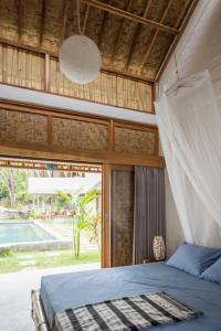 een slaapkamer met een bed en een groot raam bij Pool House Studios in Kuta Lombok