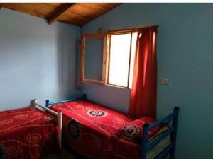 a bedroom with a red bed and a window at Las hortensias in El Hoyo