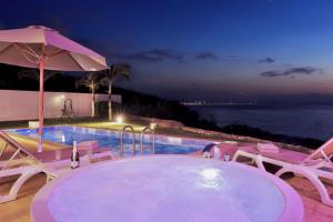 a swimming pool with chairs and an umbrella at Crystal Villa Miyakojima Sunayama Beach in Miyako Island