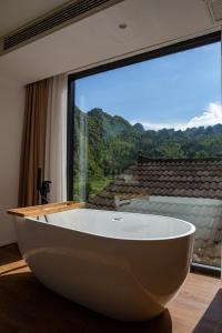 a large bath tub in a room with a large window at Fanzhu Hotel in Xingyi