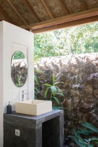 a bathroom with a sink and a stone wall at Pool House Studios in Kuta Lombok +33 photos