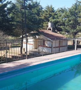 a fence next to a swimming pool with a house at La Casita de Marley in Villa Santa Cruz del Lago