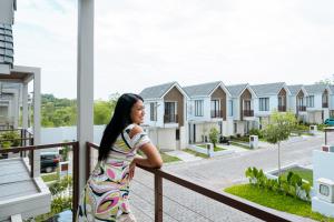 a woman standing on a balcony looking out at houses at House of Sanctuary Jimbaran at Damara Village in Jimbaran