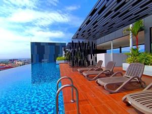 a row of chaise lounge chairs next to a swimming pool at The Horizon Ipoh 3BR L16 by Grab A Stay in Ipoh