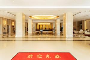 un grand hall avec un tapis rouge au milieu dans l'établissement Hua Long Hotel Lancang, à Lancang