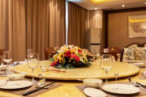 a table with glasses and a bouquet of flowers on it at Hua Long Hotel Lancang in Lancang