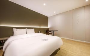 a bedroom with a large white bed and a desk at Hotel Venesian in Pohang