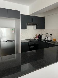 a kitchen with black and white counters and a refrigerator at Cosyplace at Mi Vida in Garden city in Nairobi