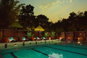 a swimming pool at night with chairs and umbrellas at Olde Bangalore Resort and Wellness Center in Devanahalli-Bangalore