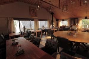 a restaurant with wooden tables and chairs and windows at Human & Horse Hotel in Kootwijkerbroek