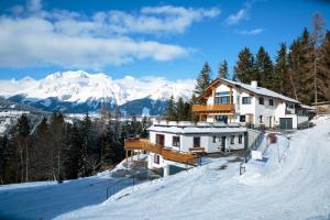 a house on a snowy hill with mountains in the background at Haus Wöhrer / Appartement Fischbacher in Schladming