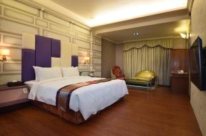 um quarto de hotel com uma cama grande e uma televisão em Summer House Motel em Tainan