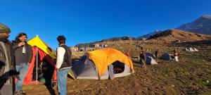 a group of people standing next to their tents at Triund Trek in Dharamshala