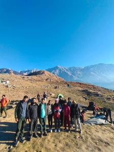 grupa ludzi stojących na szczycie góry w obiekcie Dharamshala trek and camping w mieście Dharamsala