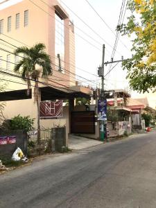 an empty street next to a building with a palm tree at Nord House Laoag in Laoag