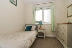 a bedroom with a bed and a dresser and a window at Tremethic in St Austell