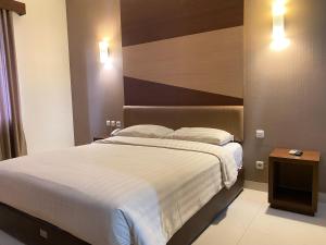 ein Schlafzimmer mit einem großen Bett und einem Kopfteil aus Holz in der Unterkunft LYNT Hotel in Jakarta