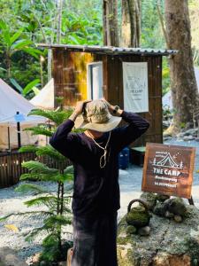 Un uomo con un cappello in piedi accanto a un cartello di The camp Maekampong a Ban Pok Nai