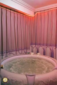 uma grande banheira num quarto com cortinas cor-de-rosa em Empire du Luxe em Iaundé