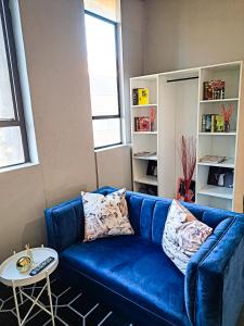 a blue couch in a living room with a table at Views on main: Craftsmanship hotel in Johannesburg