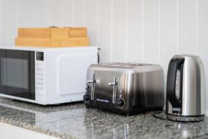 a microwave and a toaster on a kitchen counter at Relaxing 5B2BHome w Parking Walk to Brisbane River in Brisbane