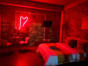a red room with a bed with a heart neon sign at Views on main: Craftsmanship hotel in Johannesburg