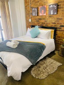 a large bed in a bedroom with a brick wall at Views on main: Craftsmanship hotel in Johannesburg