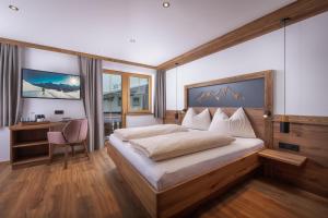 a bedroom with a large bed with a desk and windows at Pension-Appartement Sonnwend in Westendorf