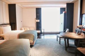 杭州市にあるJiuTai Hotel Hangzhouのベッド2台とテーブルが備わるホテルルームです。