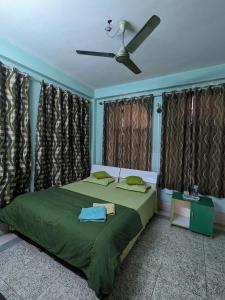 a bedroom with a green bed with a ceiling fan at Saikia Nest the Home-stay in Guwahati