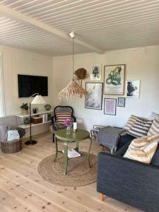 uma sala de estar com um sofá e uma mesa em Bright And Cozy Summer Cottage On A Secluded Plot em Kerteminde